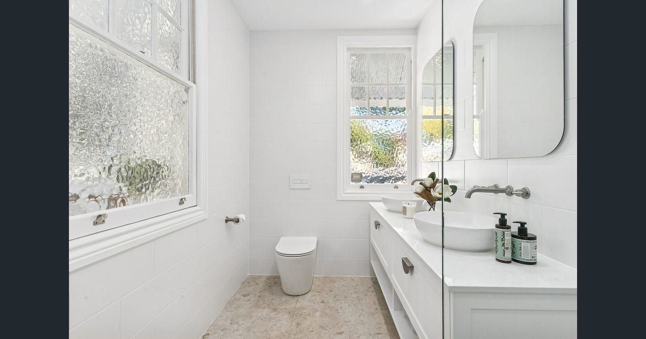 Modern laundry room with white cabinets, gray backsplash, and black appliances.  — Caprice Cabinets in Coolum Beach, QLD