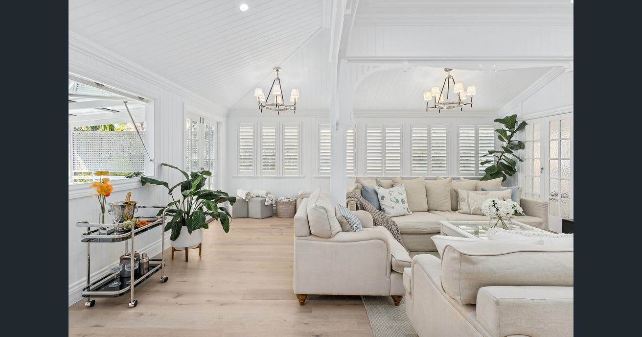 Spacious, light-filled living room with white walls, beige furniture, chandeliers, and wooden floors — Caprice Cabinets in Coolum Beach, QLD