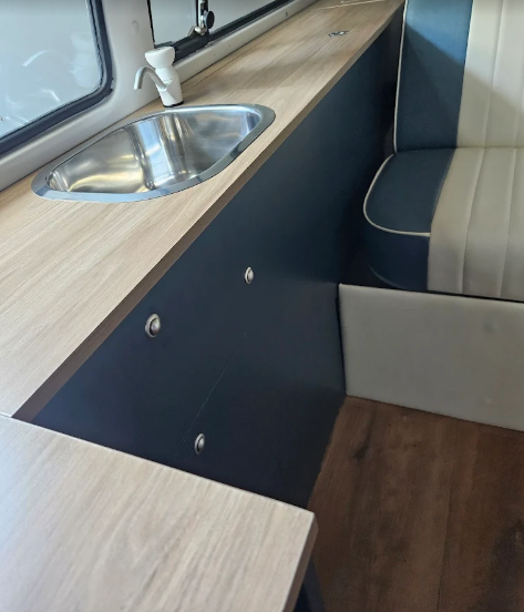 Camper van interior with sink, wood countertops, dark wall, and seating. — Caprice Cabinets in Maroochydore, QLD