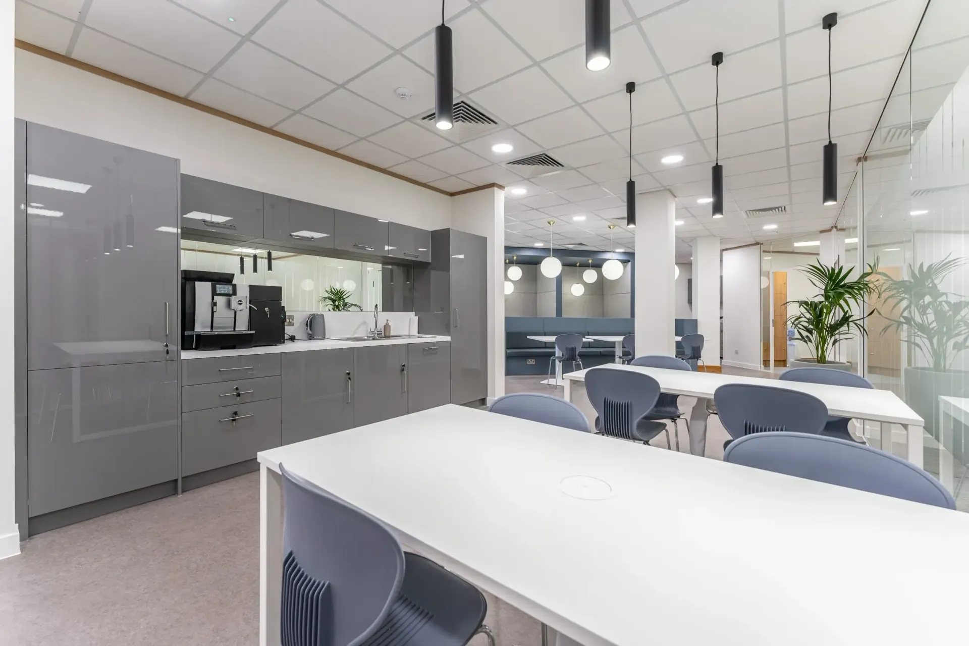 Modern office break room with gray cabinets, white tables, blue chairs, and hanging lights. — Caprice Cabinets in Brisbine, QLD