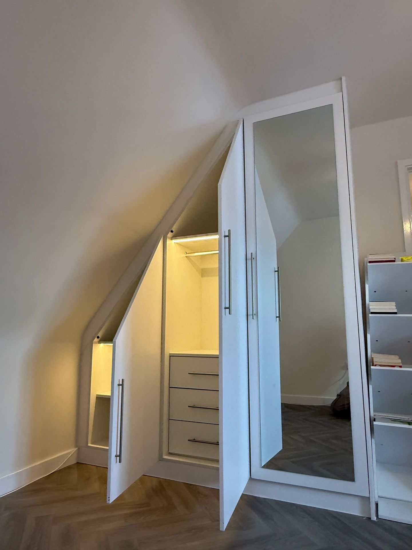 White closet built into an angled attic space with doors open, showcasing hanging rod, drawers, and mirror. — Caprice Cabinets in Caloundra, QLD