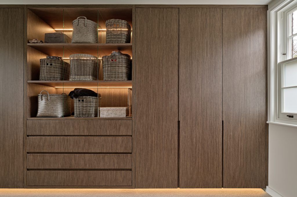 Built-in wooden closet with open shelves, drawers, and closed doors; lit with warm lights. — Caprice Cabinets in Maroochydore, QLD