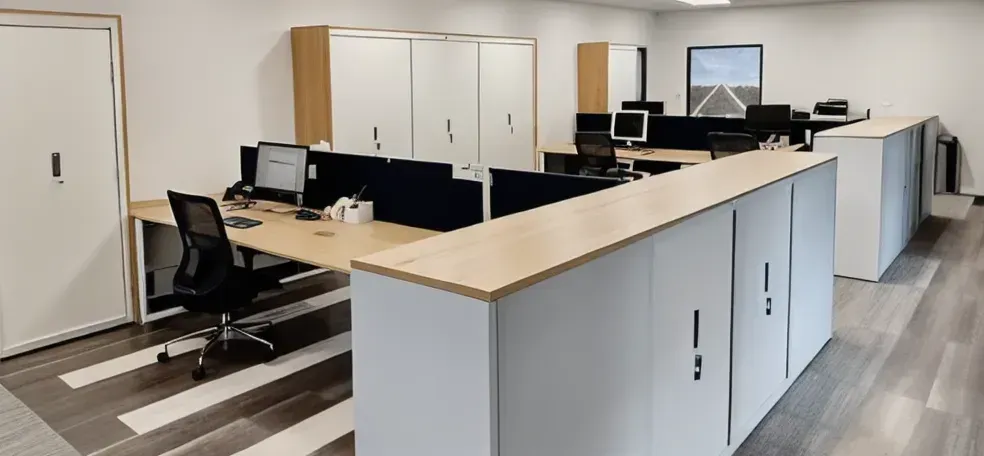 An office with multiple desks, computer screens, storage cabinets, and a door. — Caprice Cabinets in Caloundra, QLD