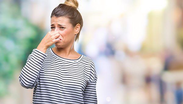 woman holding nose because of smelly septic tank