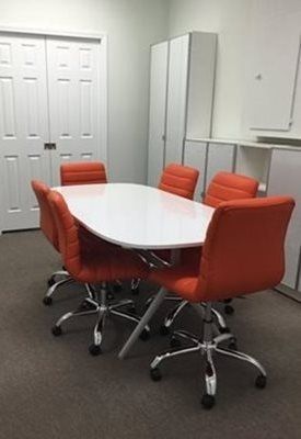 A conference room with a long white table and orange chairs at Riverside Pediatrics.