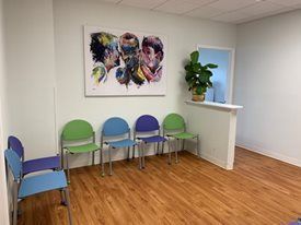 A waiting room  at Riverside Pediatrics with chairs and a painting on the wall.