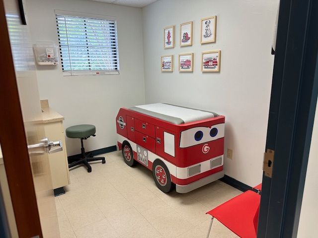 A pediatrician's exam room with a toy fire truck exam table at Riverside Pediatrics.