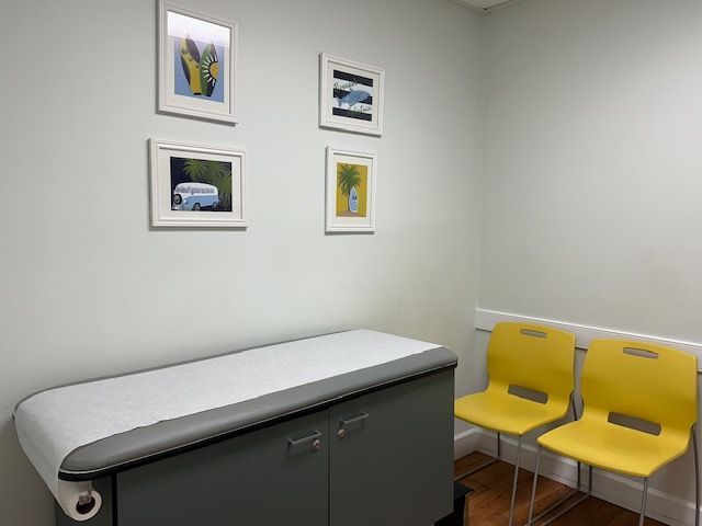 A pediatrician's office with a table and two yellow chairs at Riverside Pediatrics.
