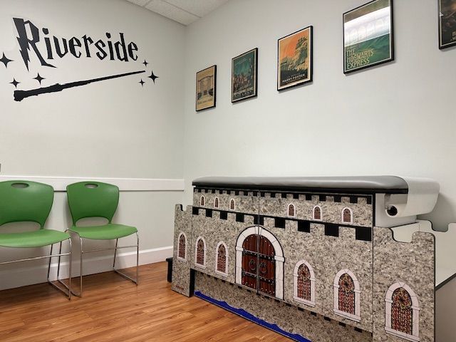 A waiting room at Riverside Pediatrics with two green chairs and a castle shaped table.