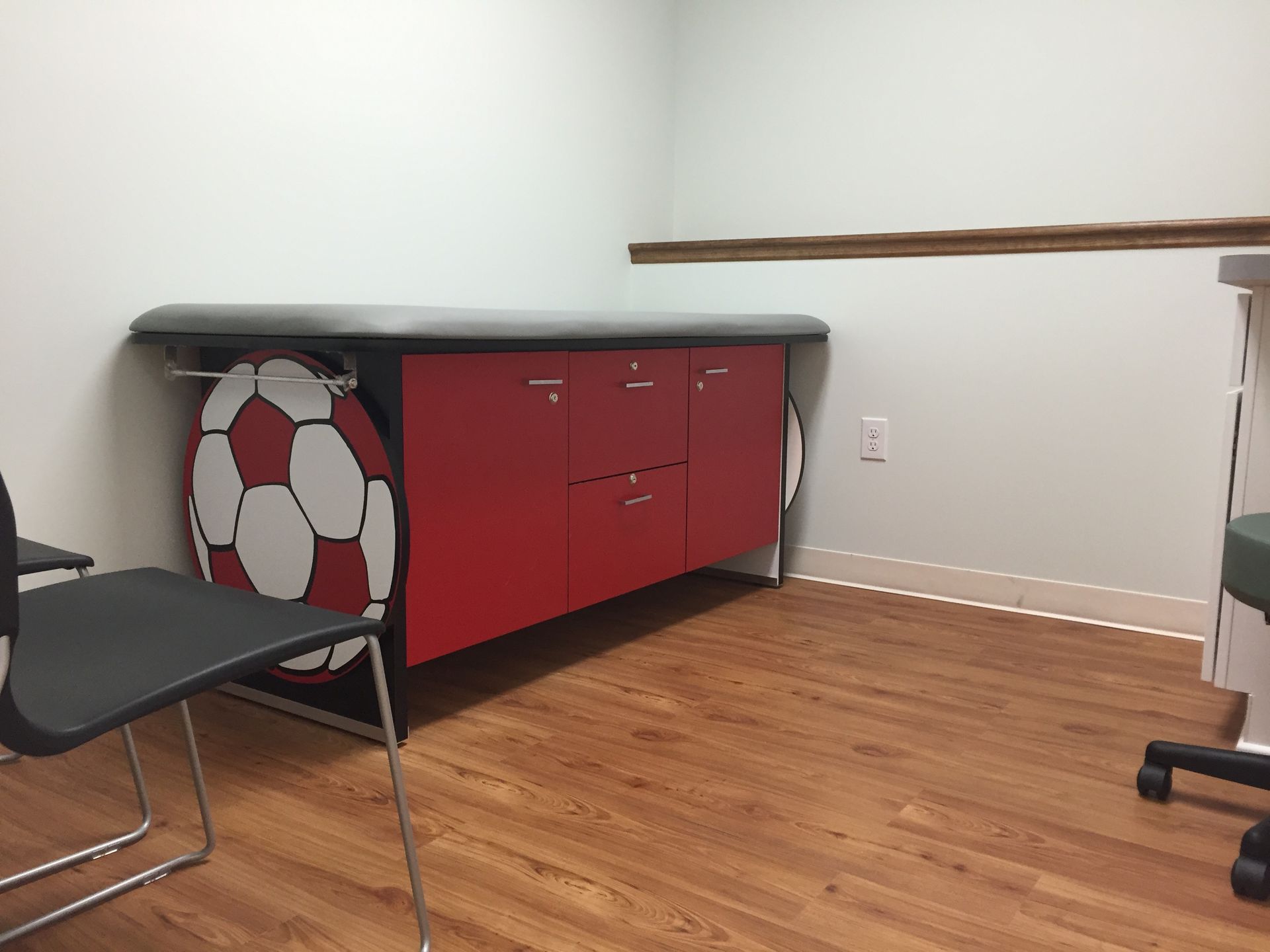 A pediatrician's office with a red table and a soccer ball on it at Riverside Pediatrics.