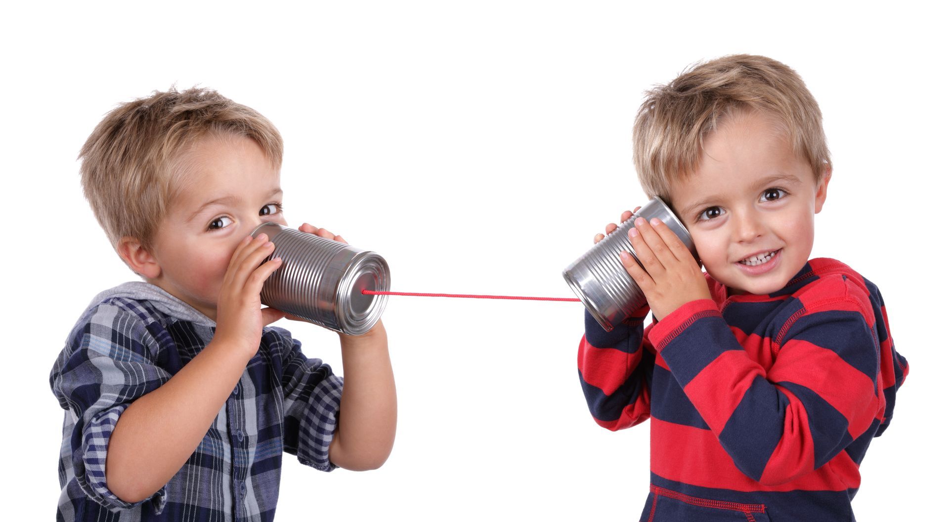 Two young boys are talking on a tin can phone