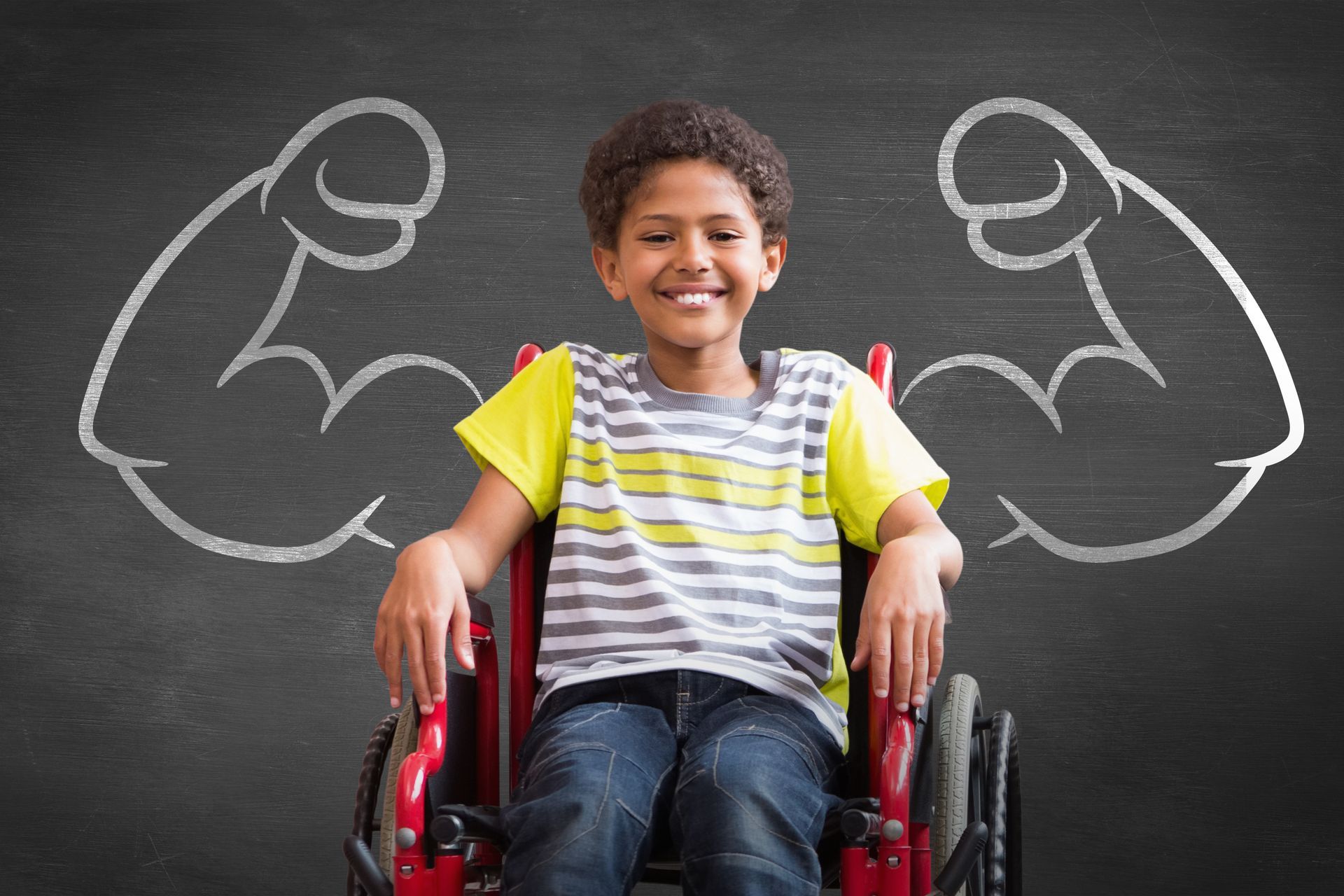 A young boy in a wheelchair with muscles drawn on a blackboard behind him.