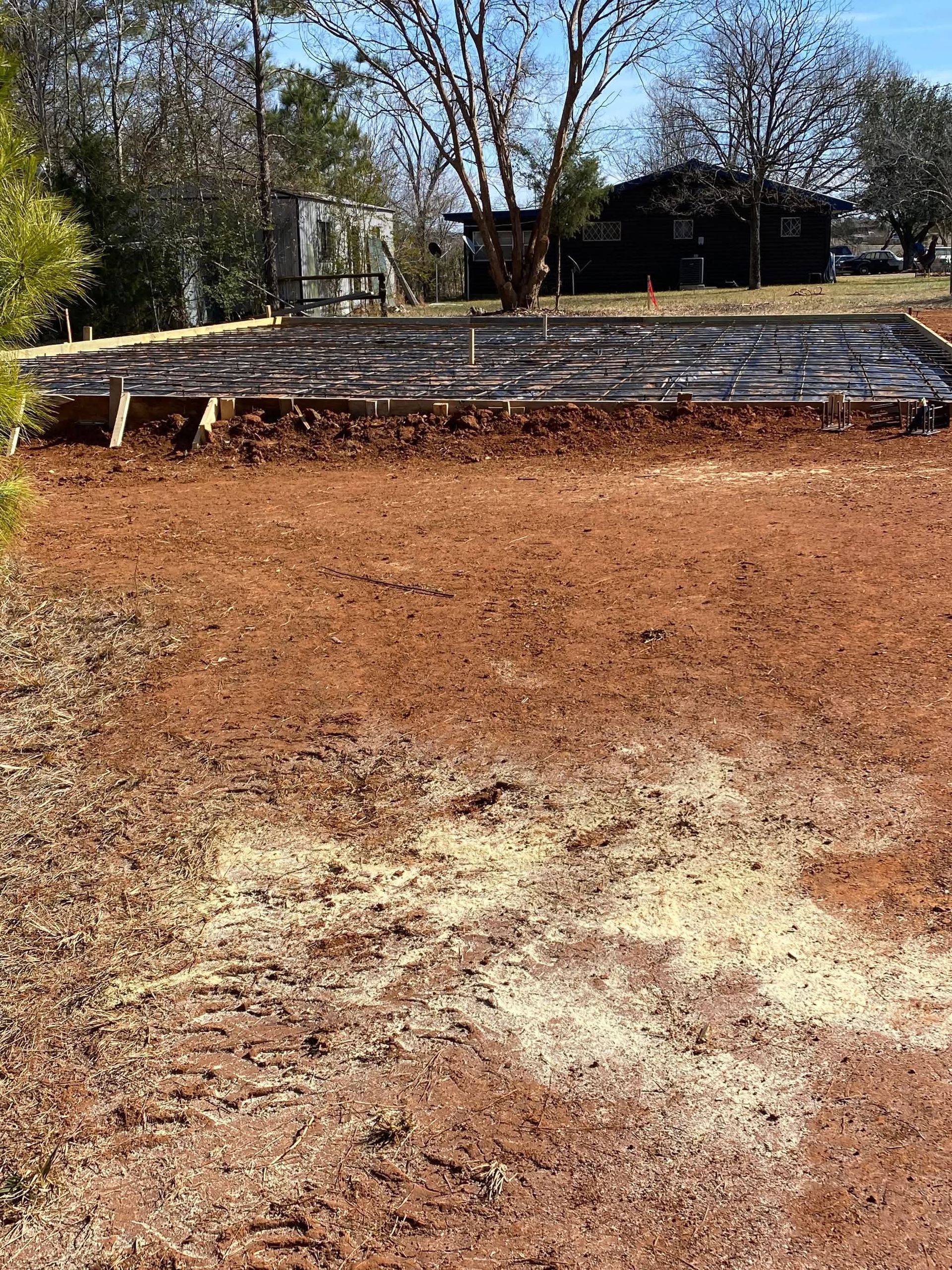 A dirt field with a house in the background.