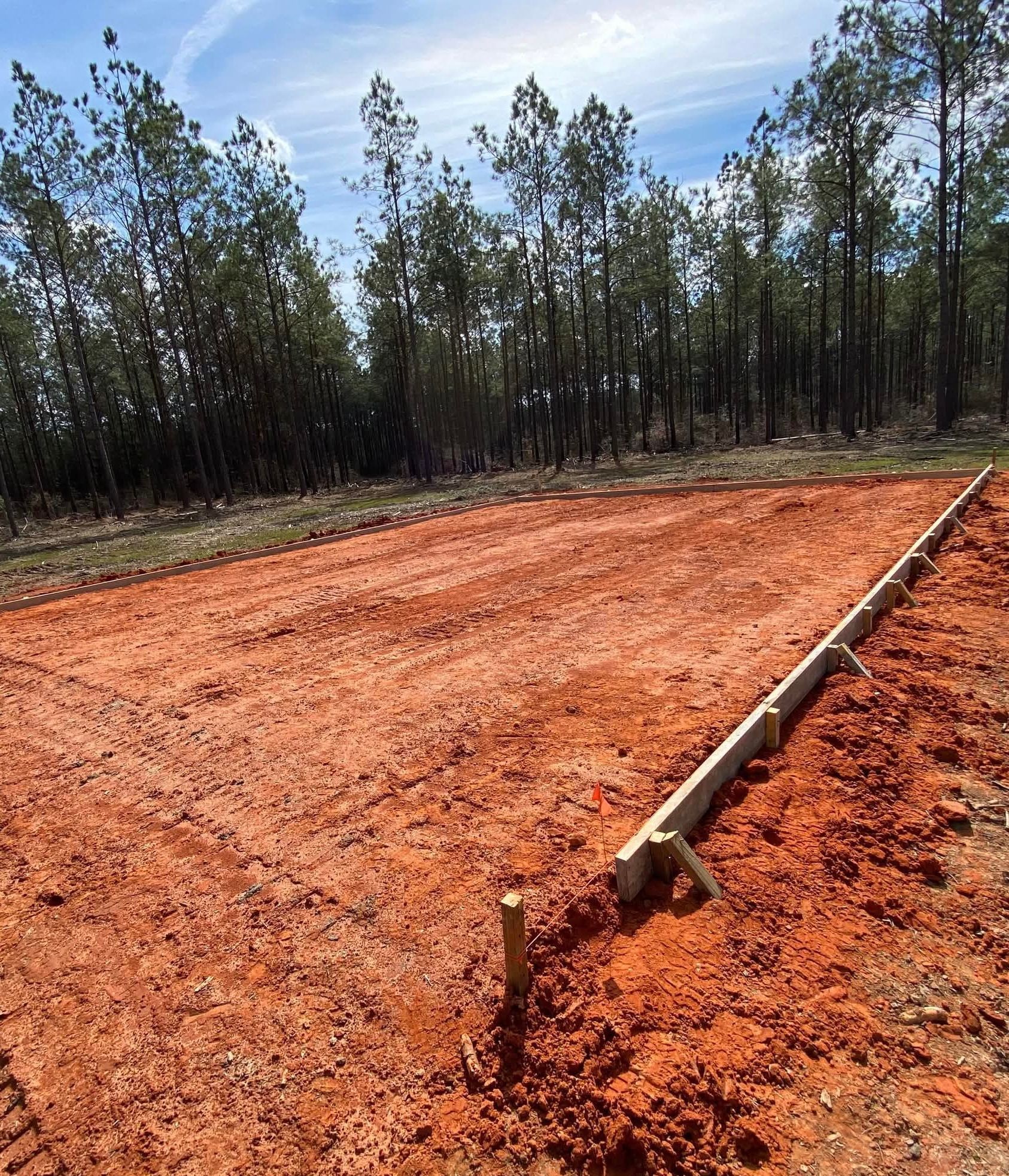 A dirt field with trees in the background and a wooden fence in the foreground.