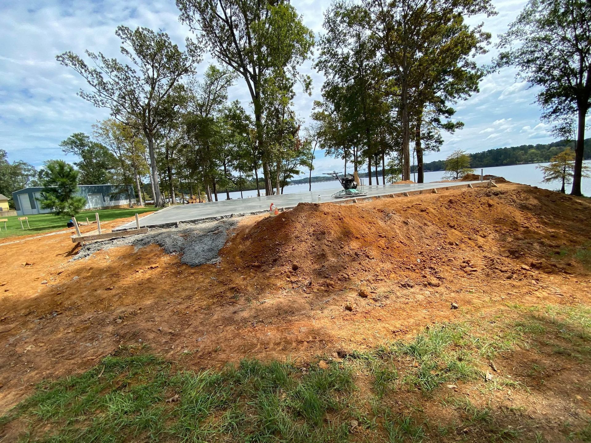 A large pile of dirt is sitting on top of a hill next to a lake.