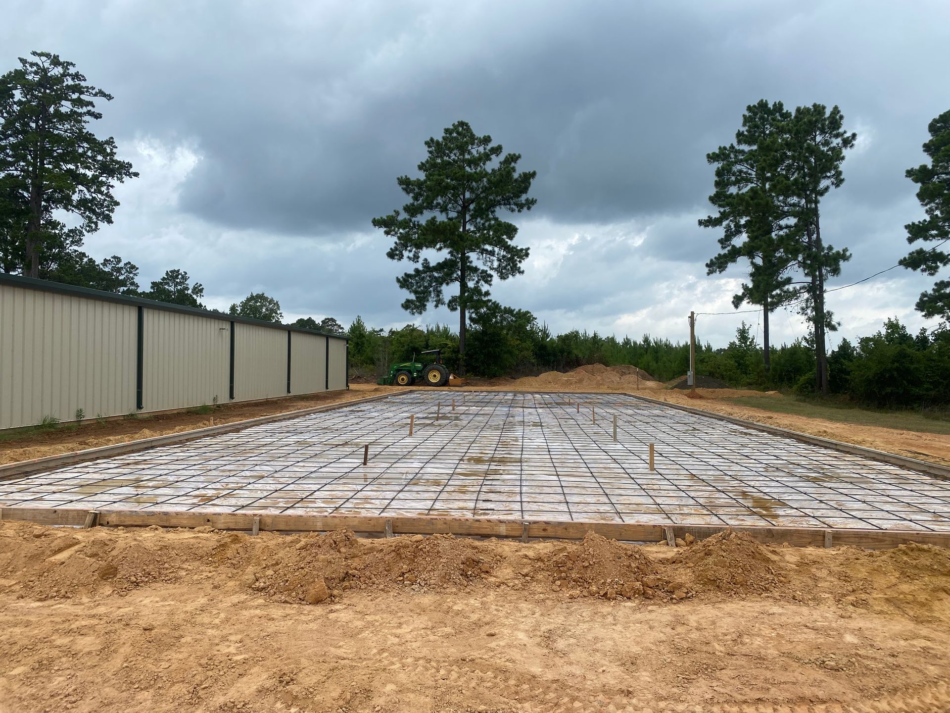 A concrete foundation is being built in a dirt field