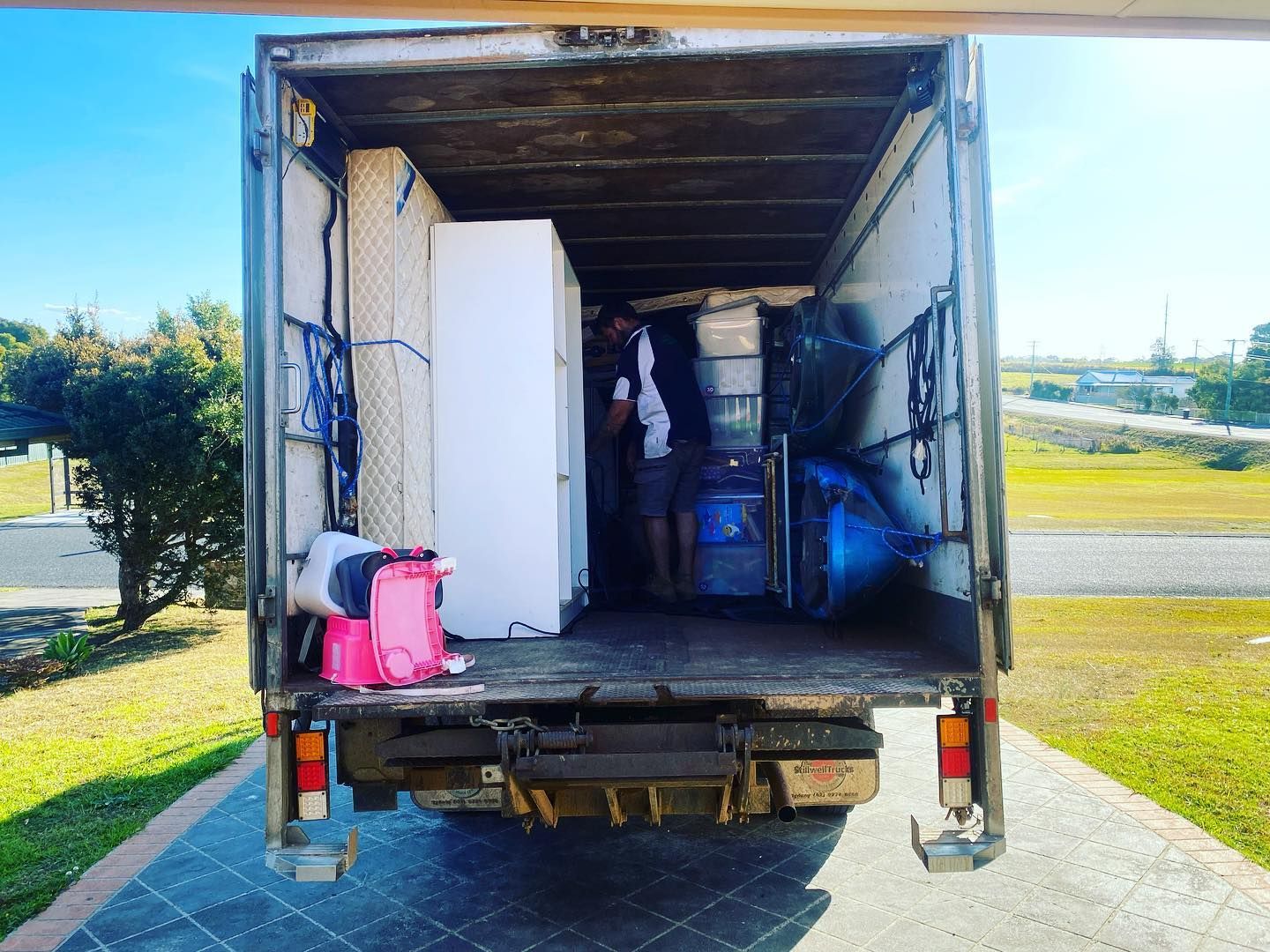 A Man Is Standing In The Back Of A Moving Truck — Easy Flow Removals In Port Macquarie, NSW