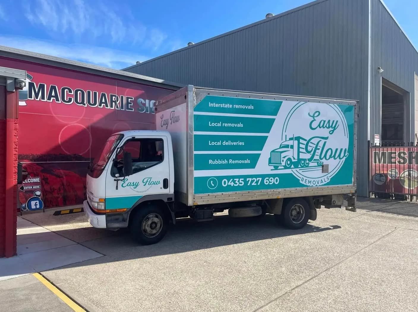 A Green And White Truck Is Parked In Front Of A Building — Easy Flow Removals In Bonny Hills, NSW