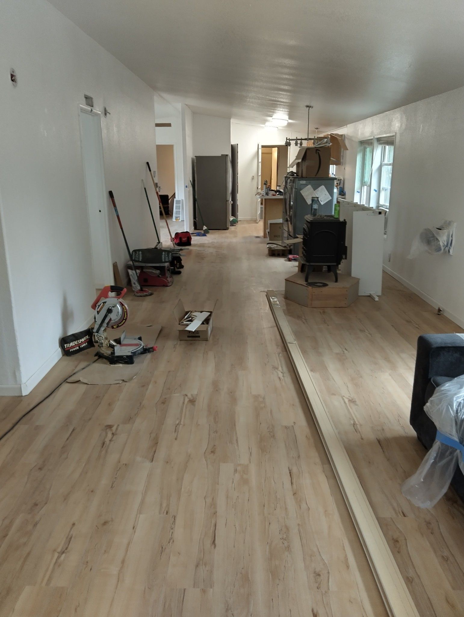 Interior with new wood flooring installation and construction tools. White walls, natural light.