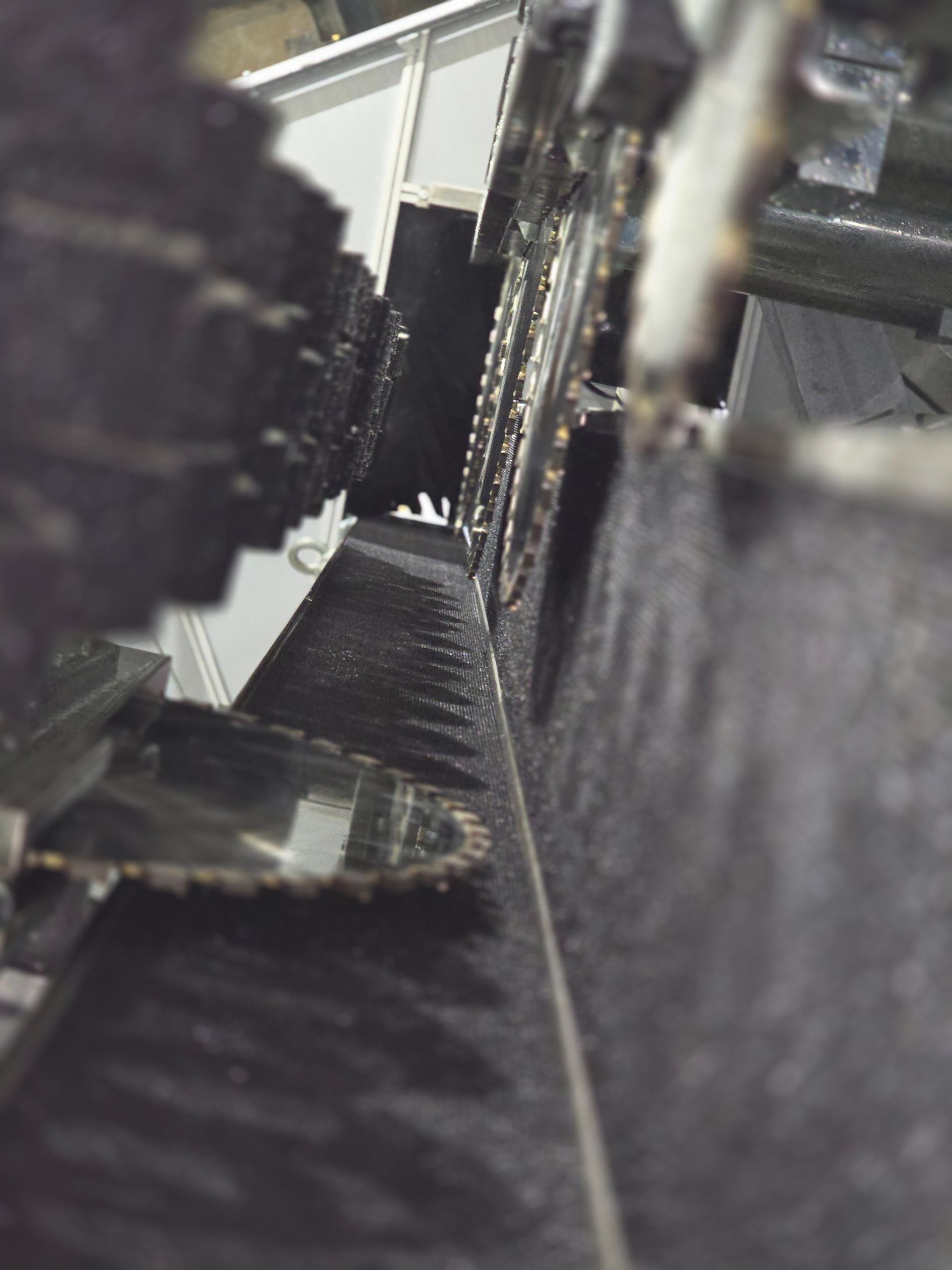 Overhead view of a machine's sharp, toothed blades; dark metal with a mirror and shadows.