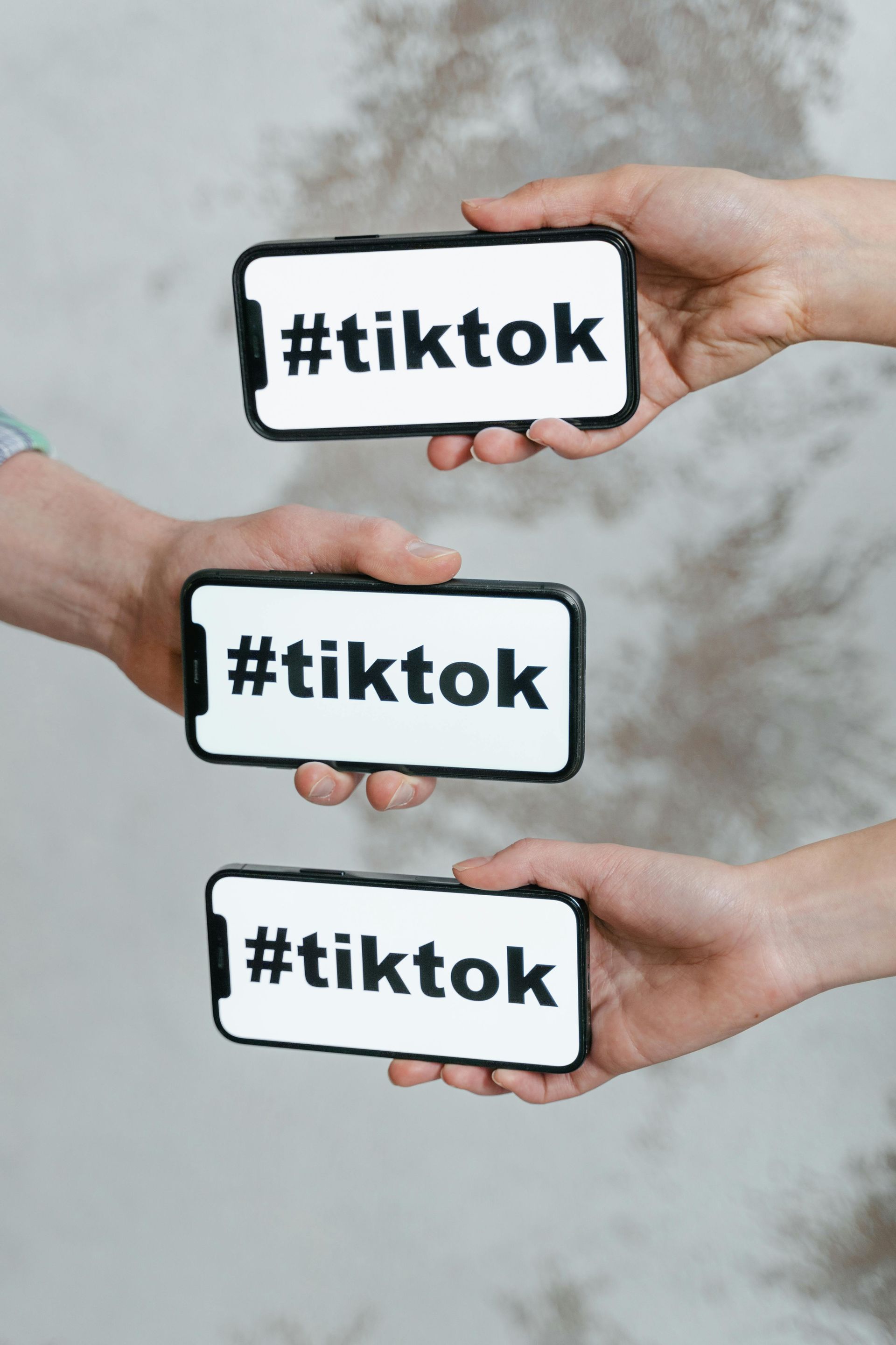 Three people are holding a cell phone with the word tiktok on it.