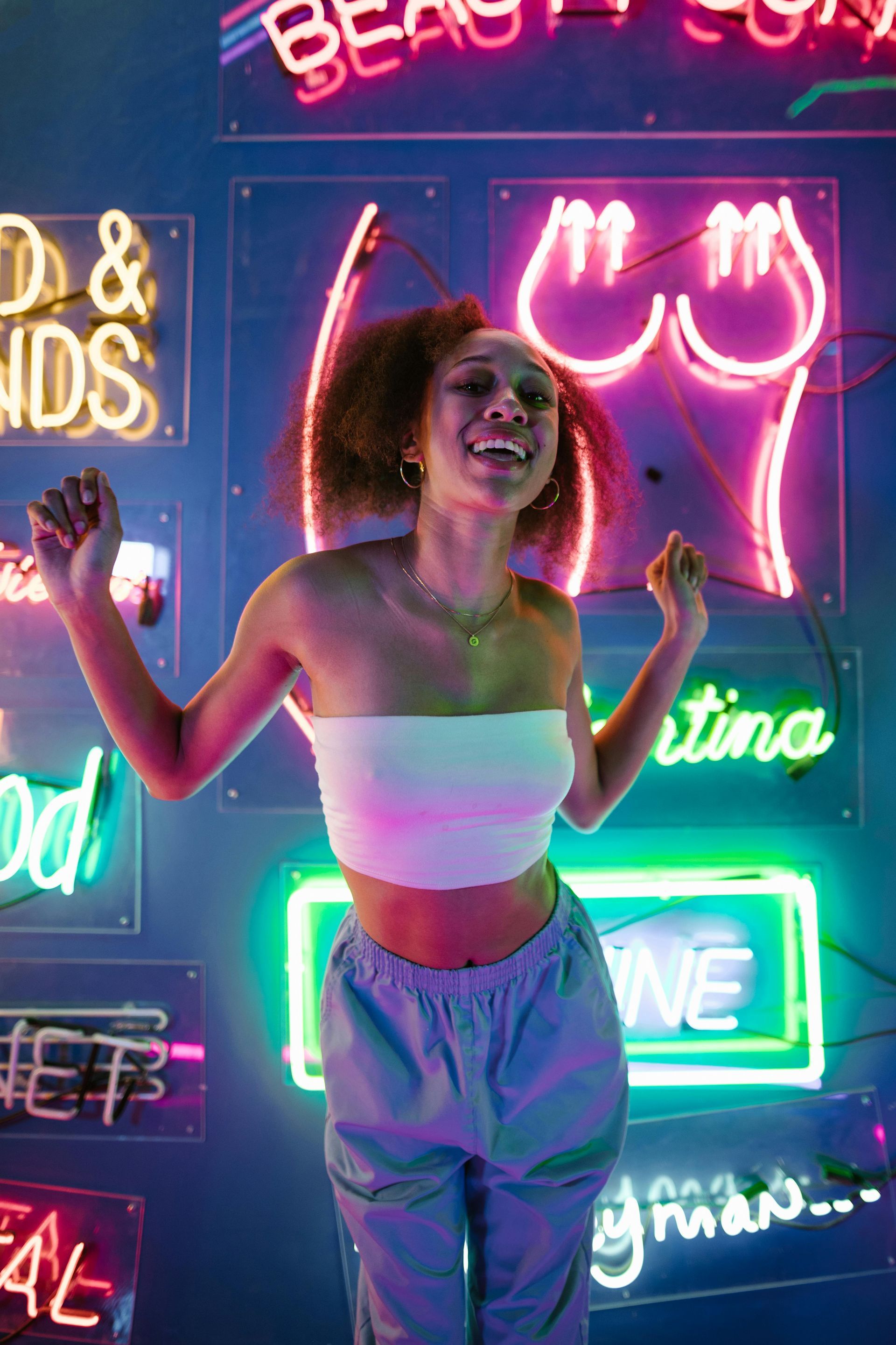 A woman is standing in front of a wall of neon lights.