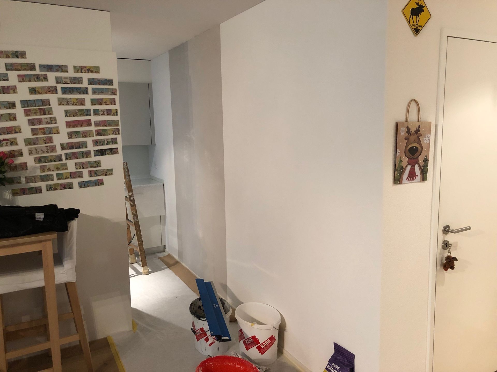 Ein Raum mit einer weissen Wand und einem roten Eimer auf dem Boden.