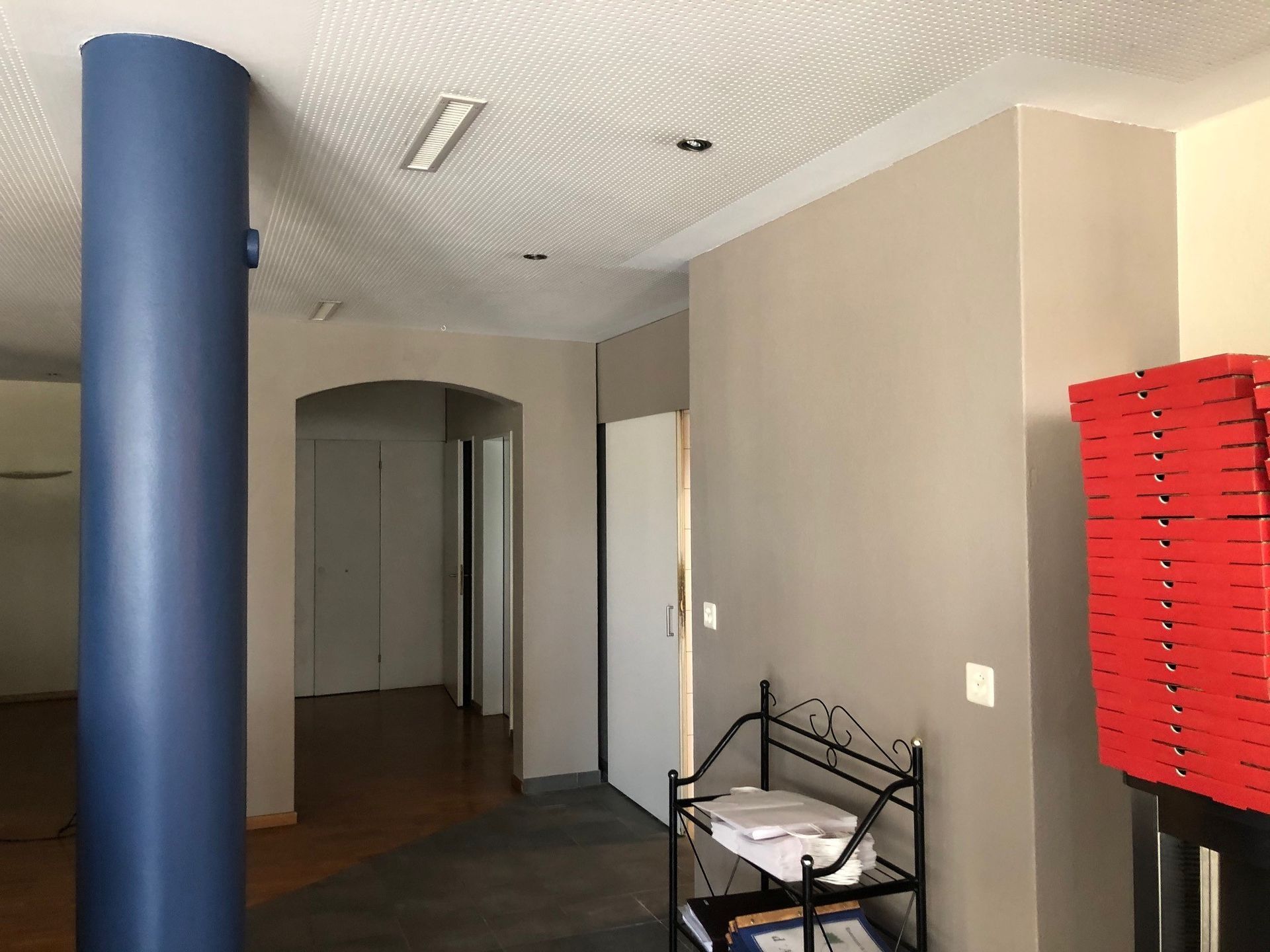 Ein Flur mit einer blauen Säule und einem Stapel roter Pizzakartons