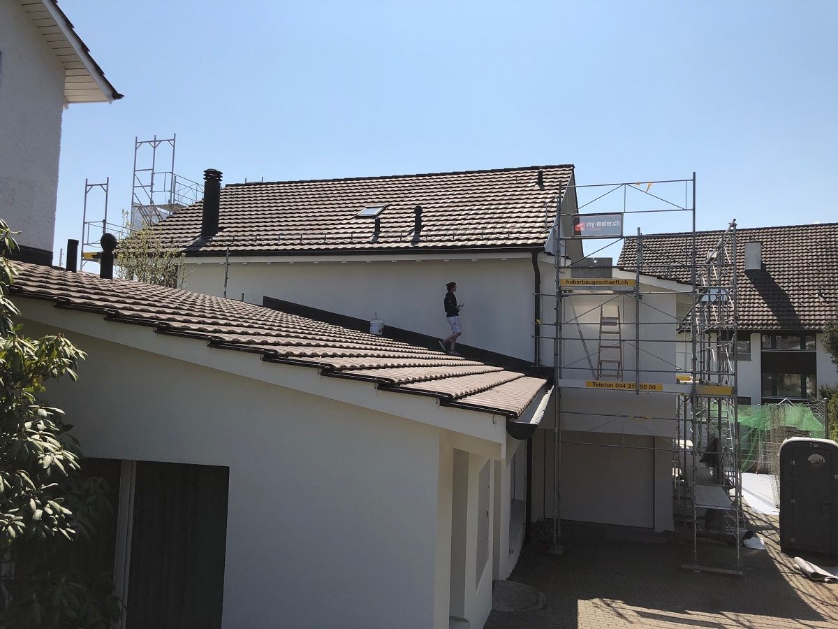 Ein weisses Haus mit Ziegeldach und einem Gerüst davor