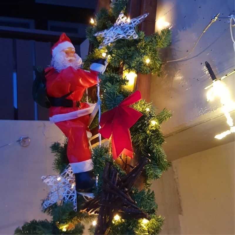 Eine Weihnachtsmannfigur klettert einen Weihnachtsbaum hinauf