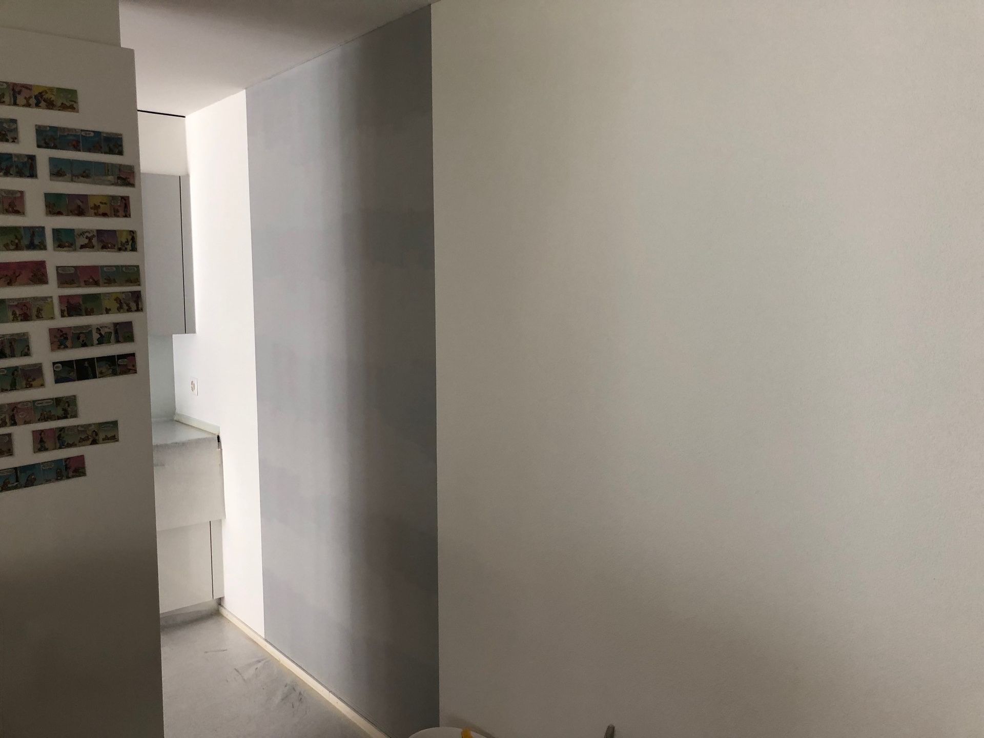 Eine weisse Wand mit einer Ziegelwand dahinter in einem Raum.