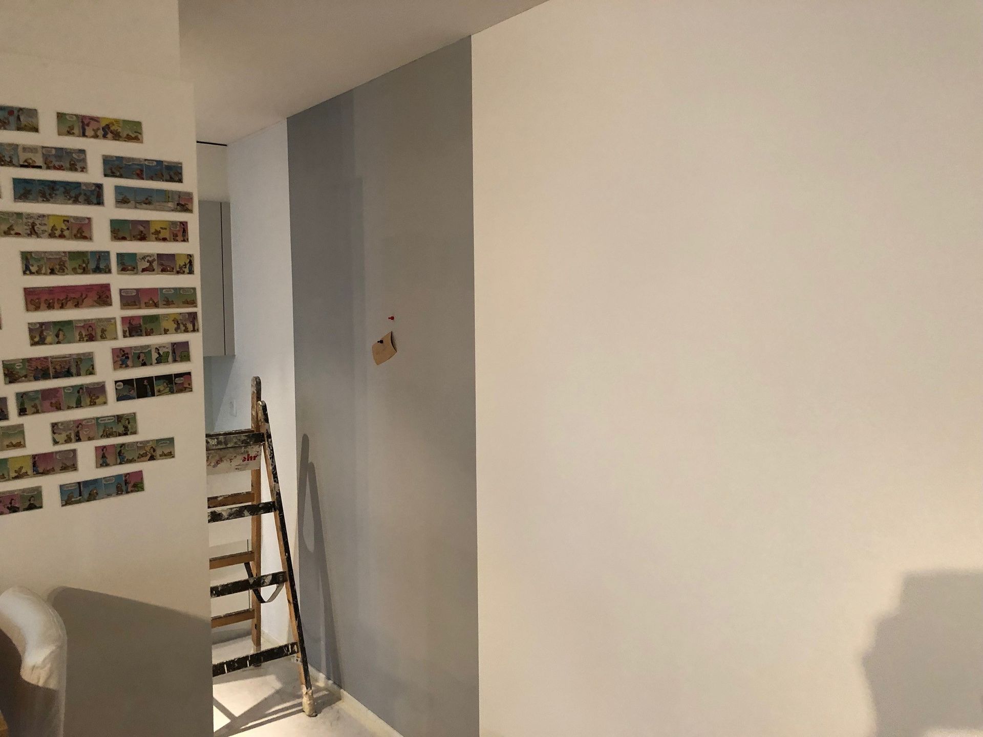 Ein Raum mit einer weissen Wand und einer Leiter darin.
