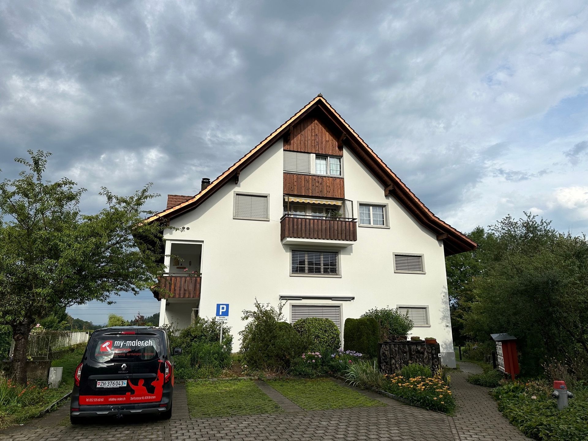 Ein weisses Haus mit einem davor geparkten roten Auto