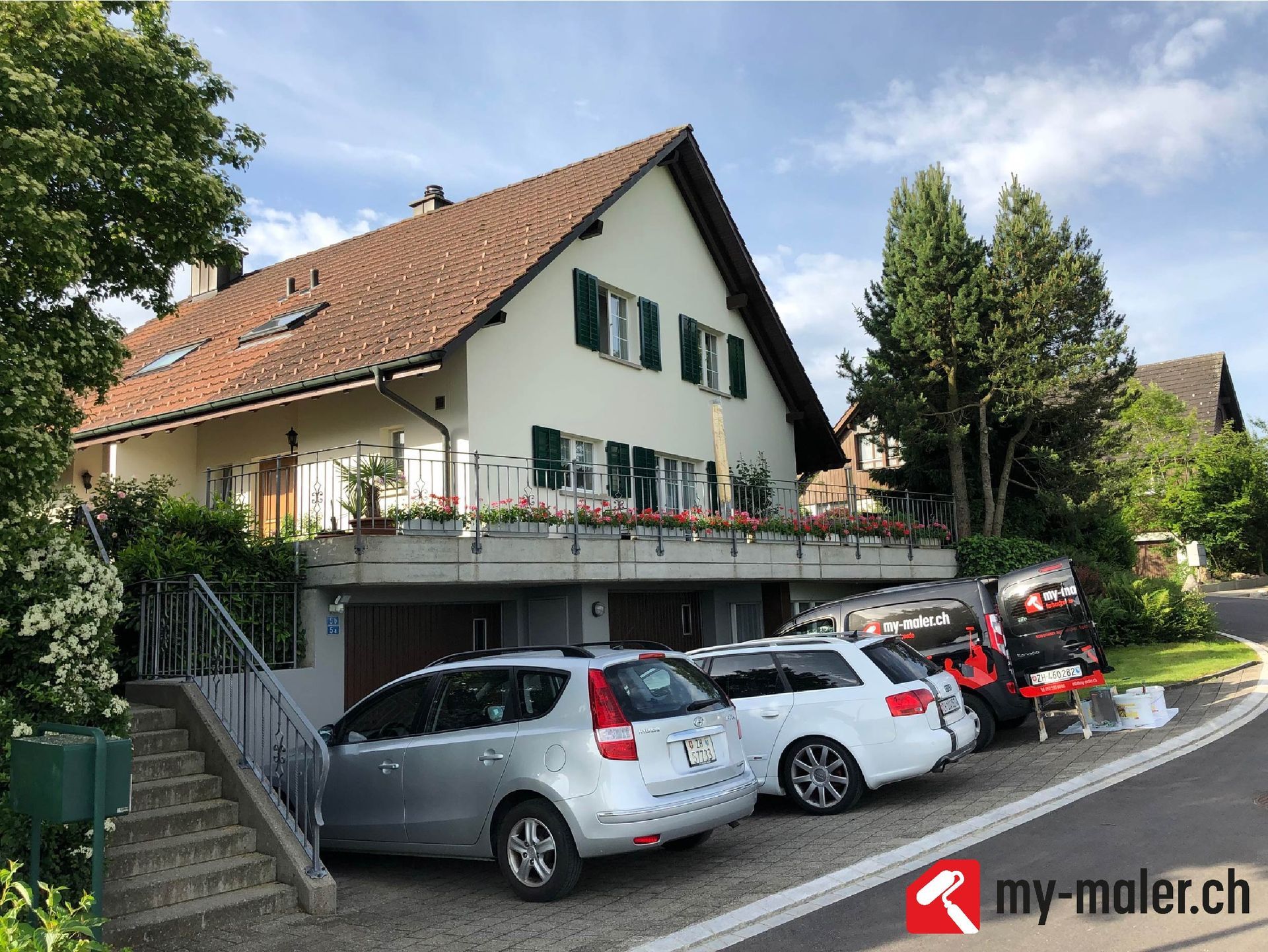 Vor einem Haus parken mehrere Autos.