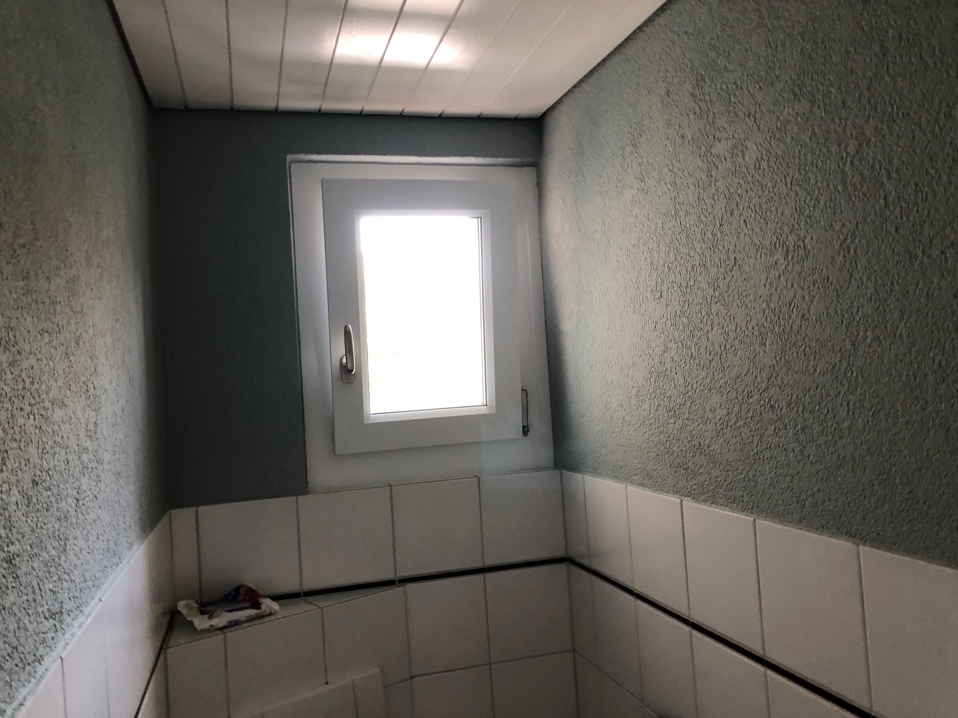 Ein Badezimmer mit Fenster und weissen Fliesen