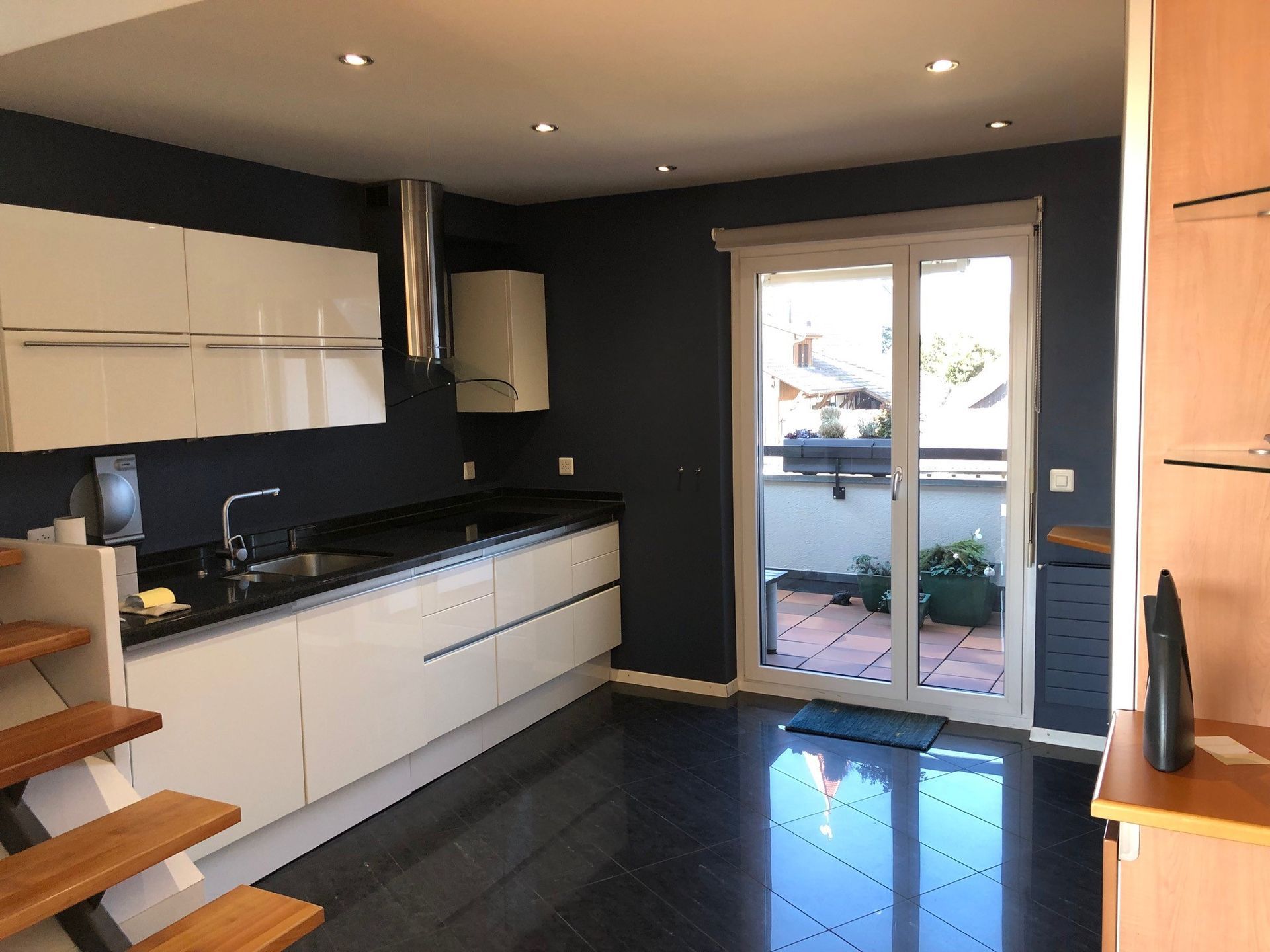 Eine Küche mit weissen Schränken und schwarzen Arbeitsplatten