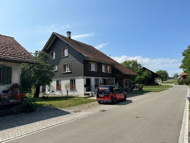 Ein roter Lieferwagen steht am Strassenrand vor einem Haus.