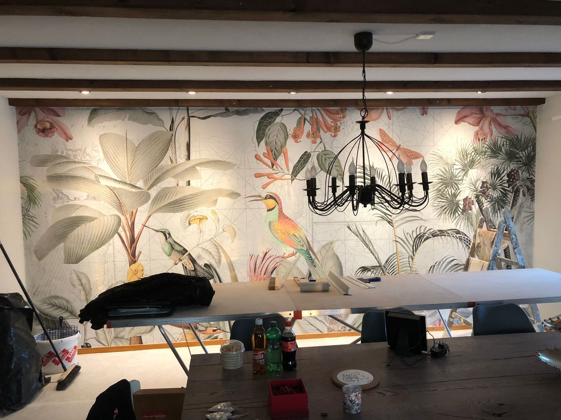 Ein Esszimmer mit einem grossen Wandgemälde an der Wand und einem Kronleuchter, der von der Decke hängt.