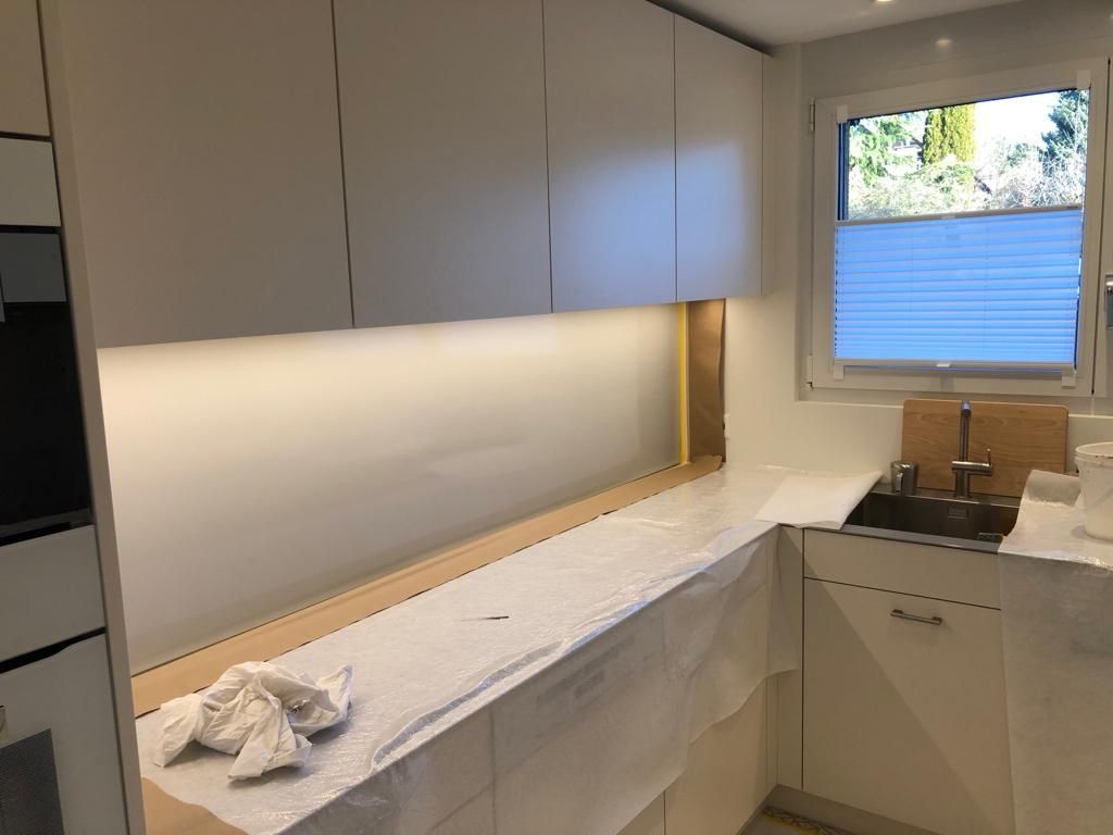 Eine Küche mit weissen Schränken, einer Spüle und einem Fenster.