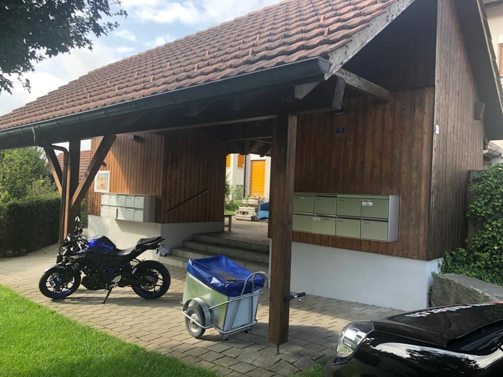 Vor einem Holzgebäude ist ein Motorrad geparkt.