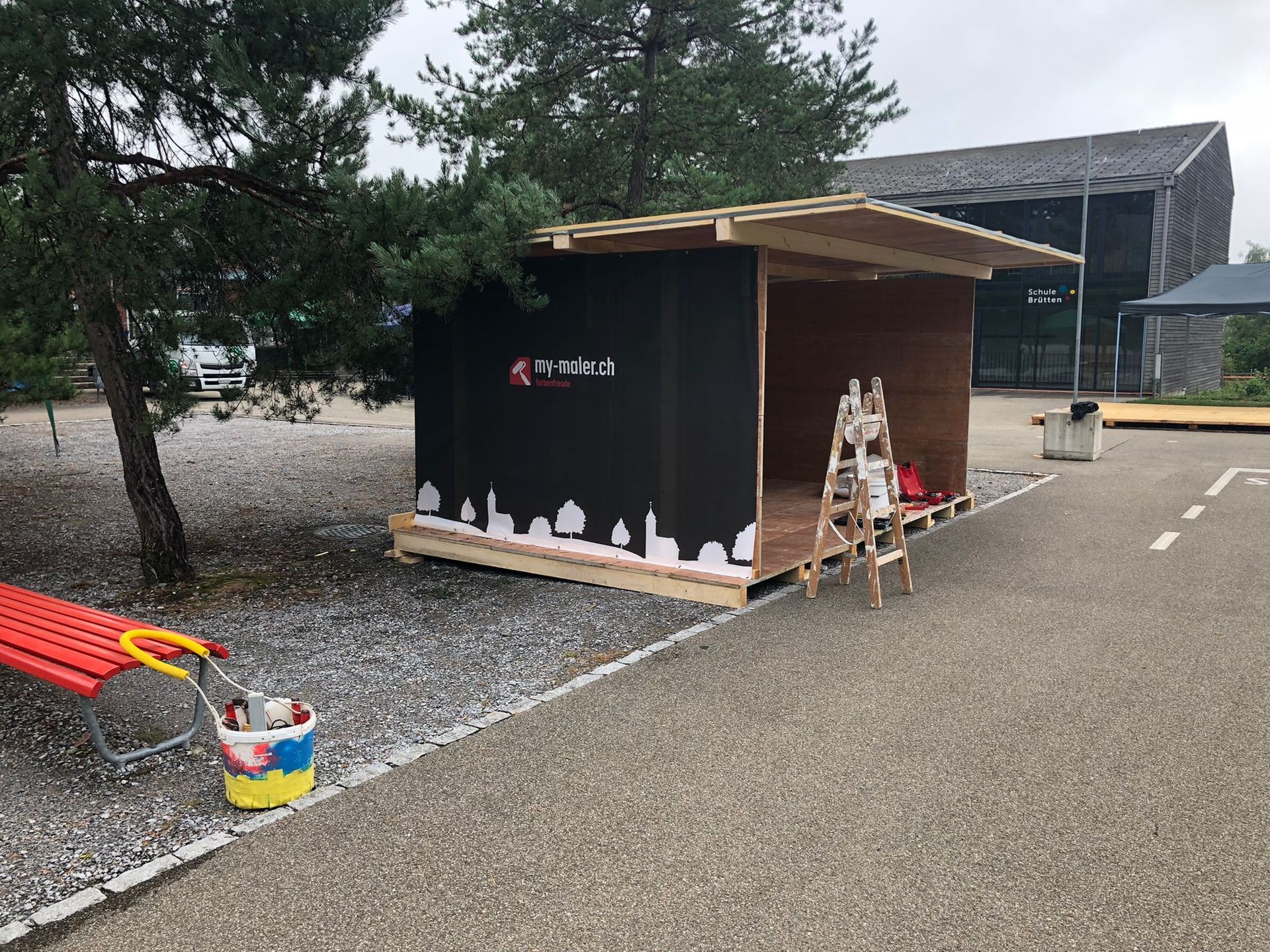 Auf einem Parkplatz wird ein kleines Holzgebäude errichtet.