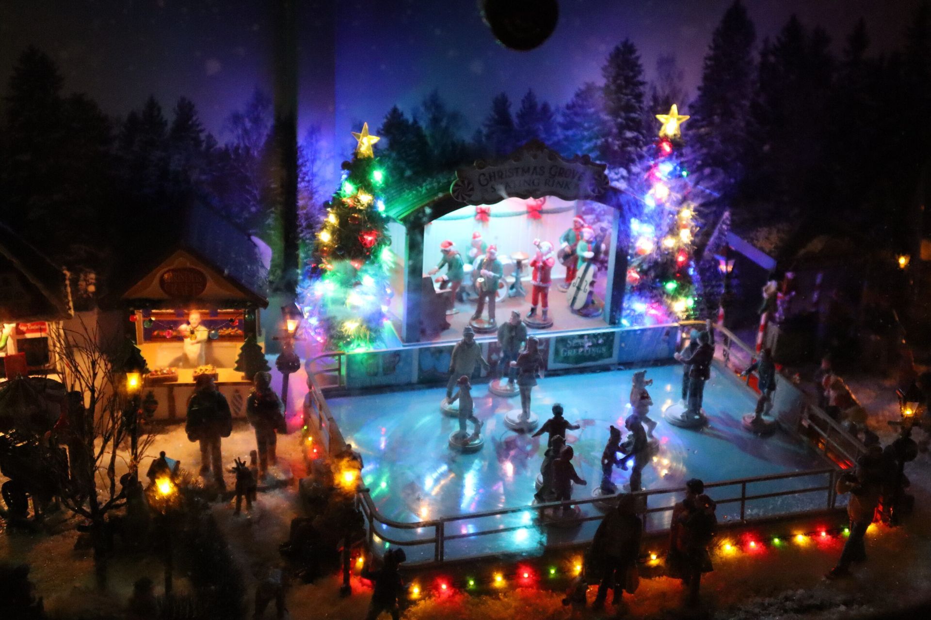 Eine Gruppe von Menschen läuft auf einer mit Weihnachtslichtern geschmückten Eisbahn Schlittschuh.