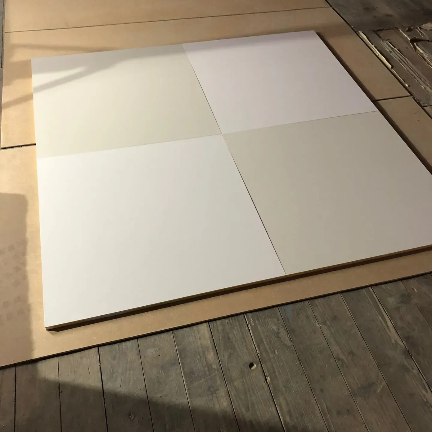 Ein Quadrat aus weissen Fliesen auf einem Holzboden