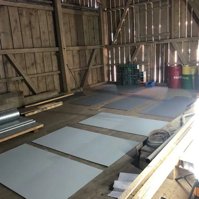 Eine grosse Holzscheune mit ein paar Fässern, auf denen Papyrus steht