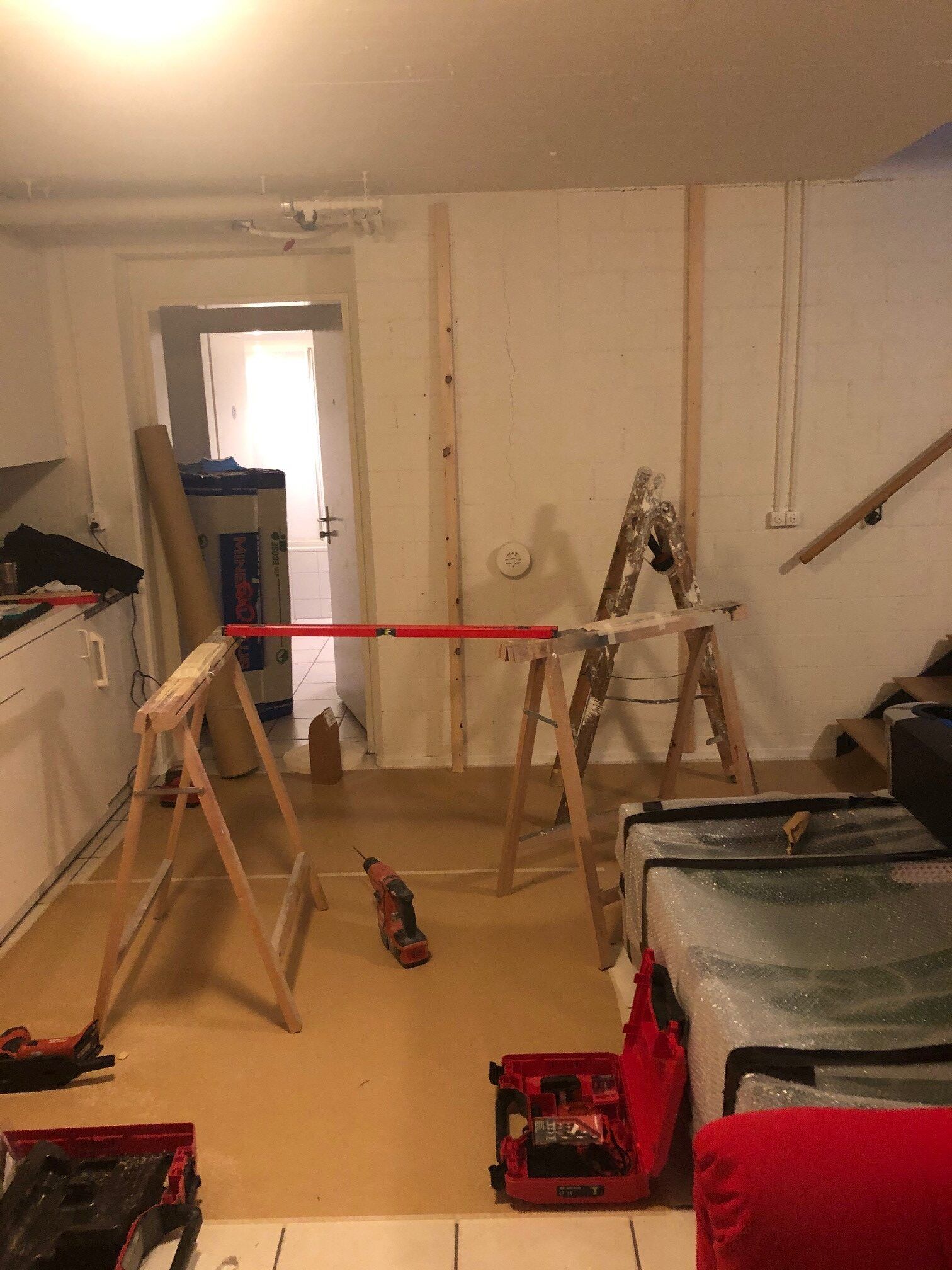 Ein Raum mit einer Leiter, einem Holzbock und einem roten Werkzeugkasten.