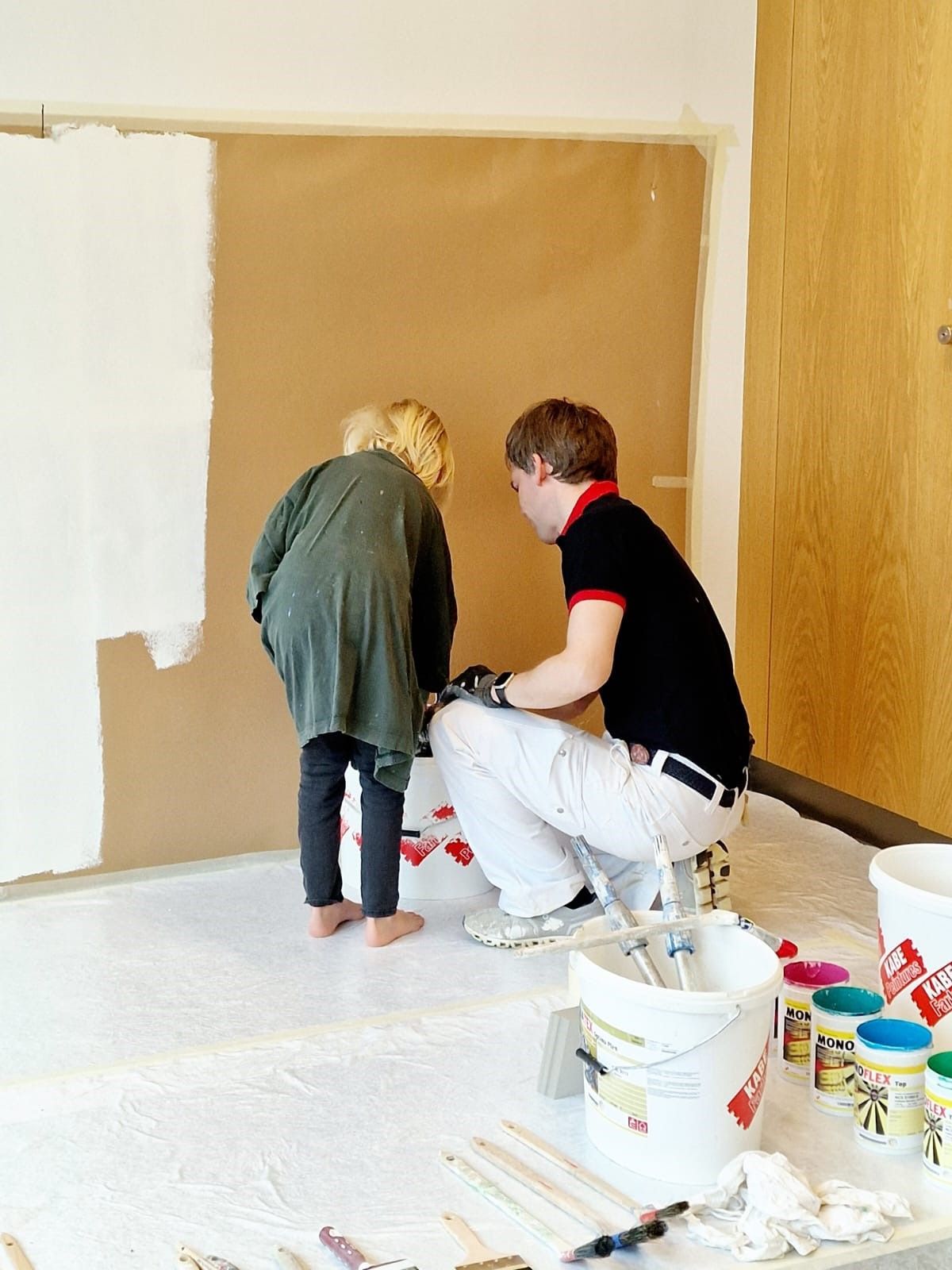 Ein Mann und ein kleines Mädchen streichen gemeinsam eine Wand