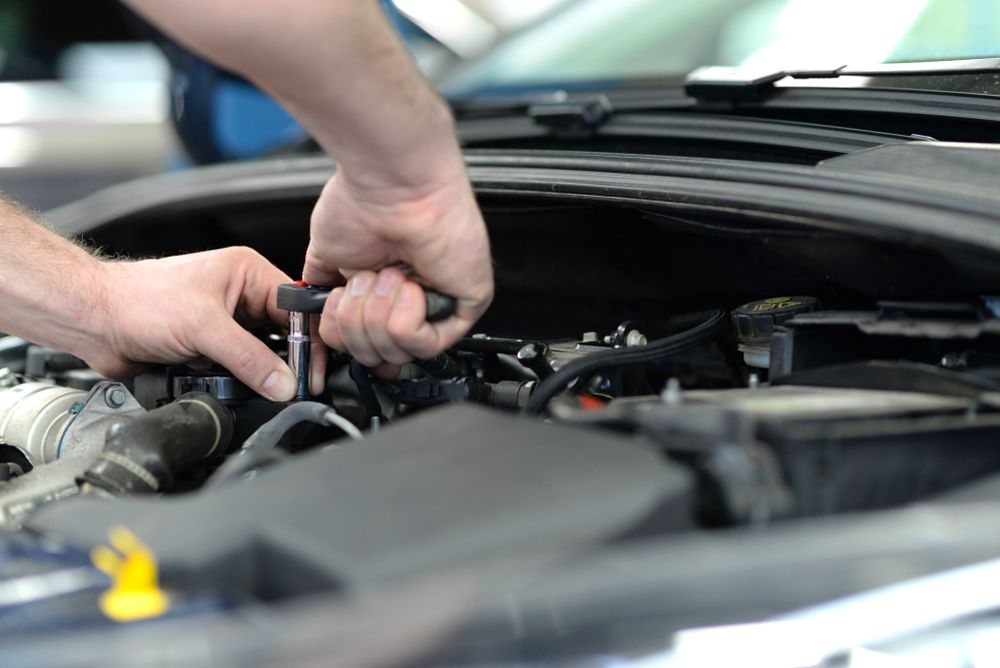 A Man Is Working On The Engine Of A Car With A Wrench — Advanced Windscreens & Service Centre In Airlie Beach, QLD