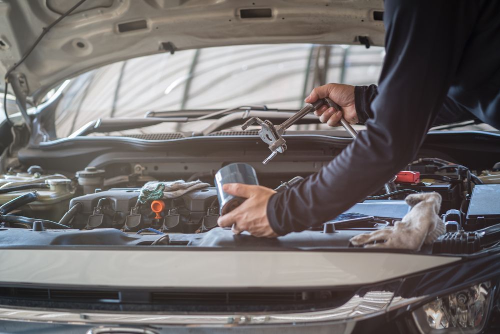 A Man Is Working On The Engine Of A Car With The Hood Open — Advanced Windscreens & Service Centre In Proserpine, QLD