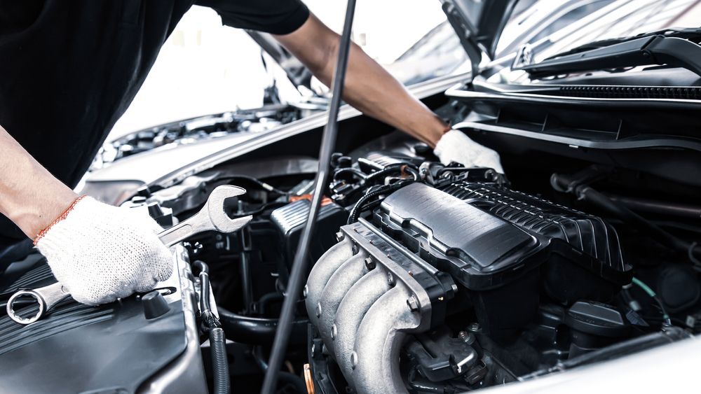 A Man Is Working On The Engine Of A Car With A Wrench — Advanced Windscreens & Service Centre In Whitsunday Region, QLD