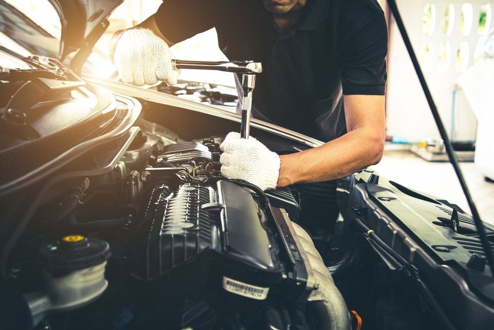 A Man Is Working On The Engine Of A Car — Advanced Windscreens & Service Centre In Whitsunday Region, QLD